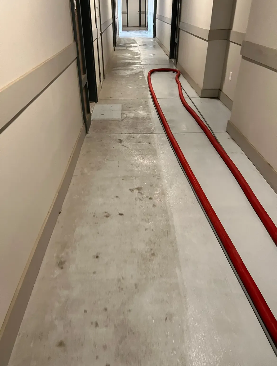 Apartment corridor concrete floor during cleaning with a cleaned section beside remaining staining in Frisco, TX