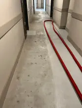 Apartment corridor concrete floor during cleaning with a cleaned section beside remaining staining in Frisco, TX