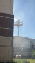Technician soft washing a brick and cast stone facade from a boom lift in Allen, TX