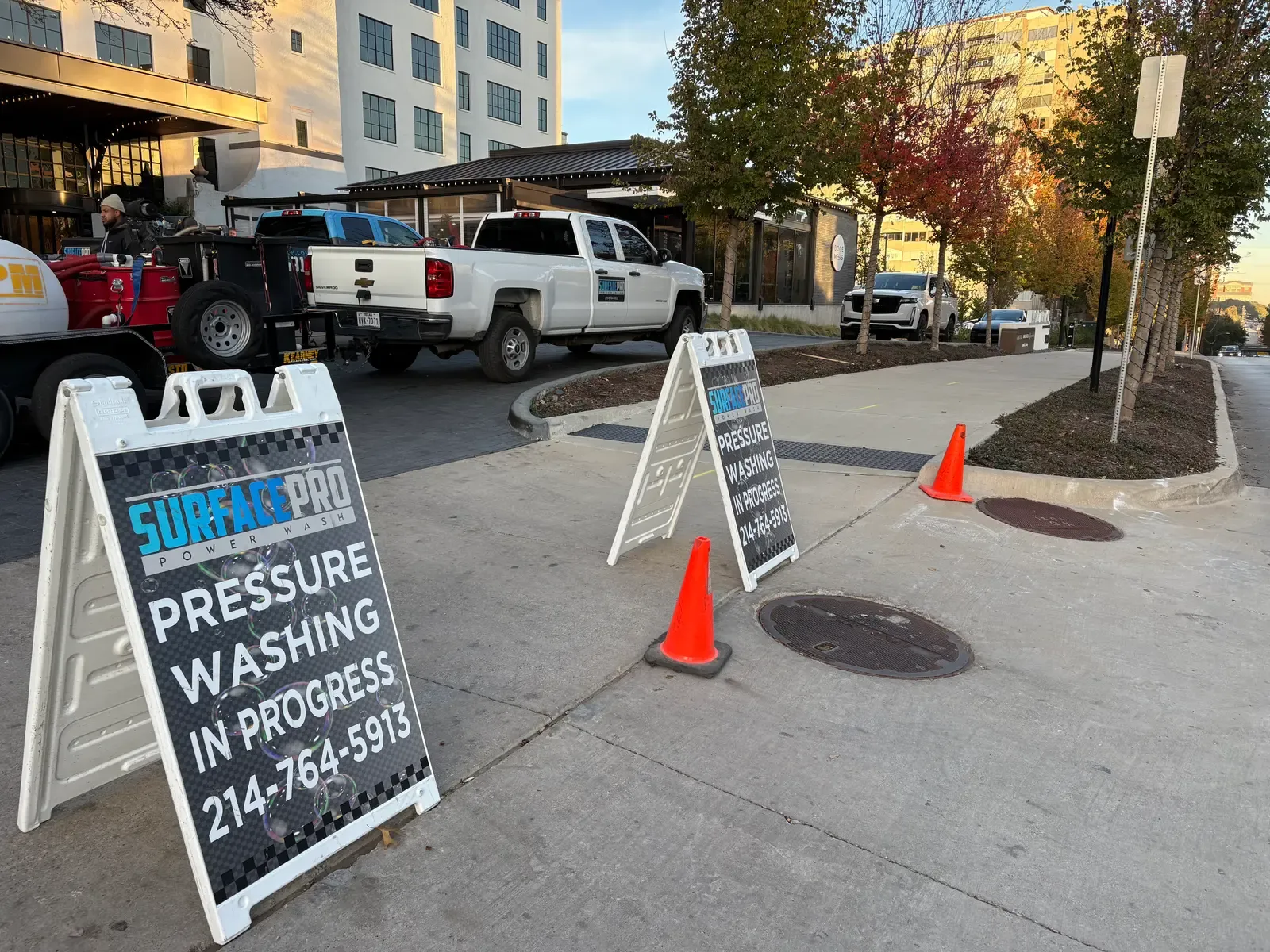 Surface Pro Power Wash trucks and work-in-progress signs staged for sidewalk cleaning on an Uptown street in Dallas, TX