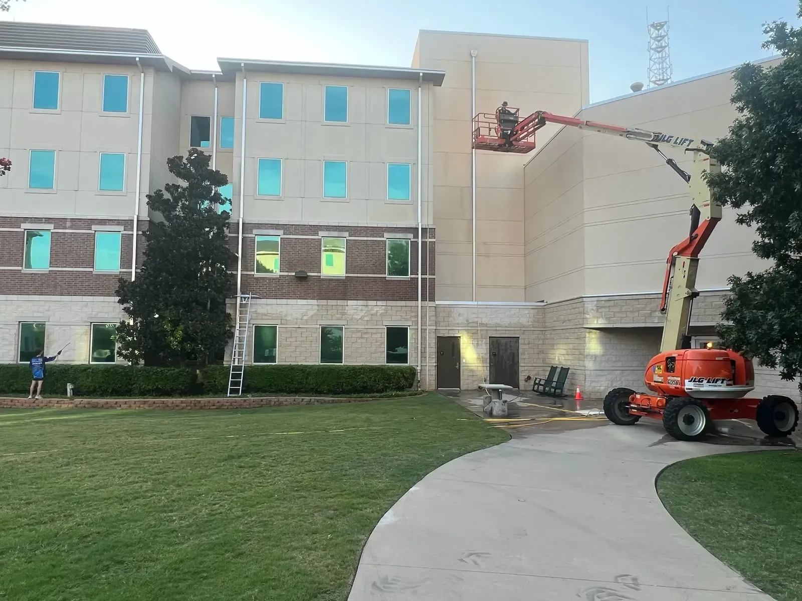 Boom lift crew cleaning the brick and stucco exterior of a four story campus building in Allen, TX