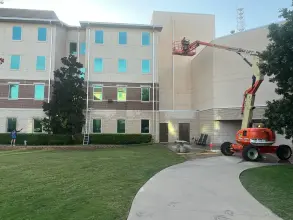 Boom lift crew cleaning the brick and stucco exterior of a four story campus building in Allen, TX