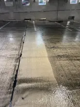 Single cleaned strip of concrete contrasting with surrounding grime on a parking garage floor in Plano, TX