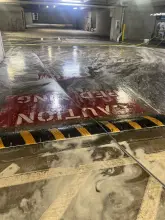Detergent foam working across a parking garage concrete floor during pressure washing in Allen, TX