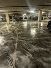 Detergent foam working on parking garage concrete between parked cars during cleaning in Dallas, TX