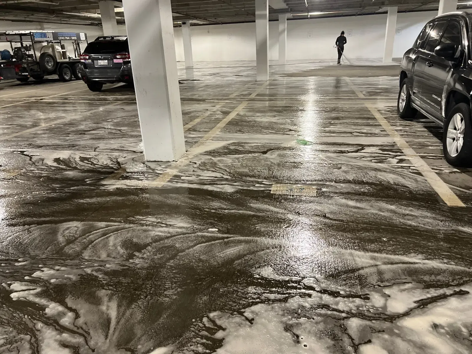 Crew member rinsing detergent from parking garage concrete during a full floor cleaning in Richardson, TX