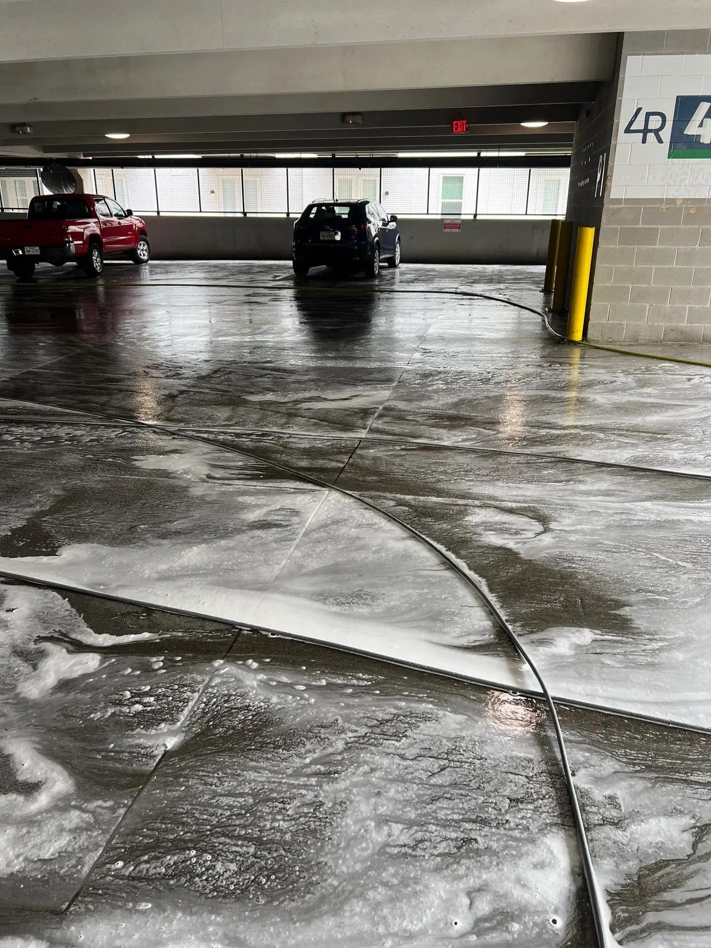 Detergent foam and rinse water across a parking structure deck during cleaning in Plano, TX