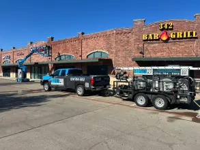 Crew using a boom lift to clean the brick facade and signage of a retail shopping center in McKinney, TX