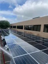 Rinse water sheeting off solar carport panels during a canopy washing at an office building in Richardson, TX